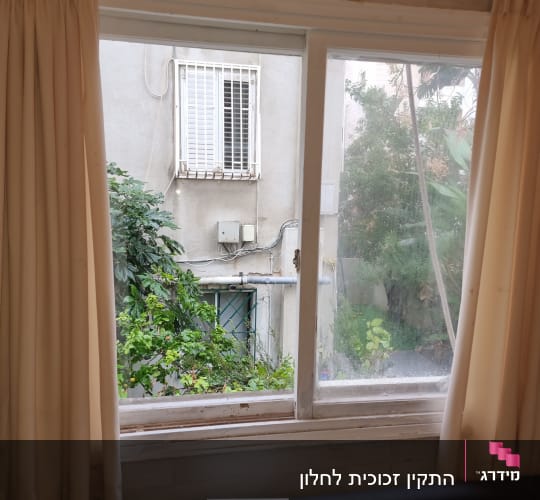 חלון זכוכית עם וילונות בצדדים ונוף חיצוני